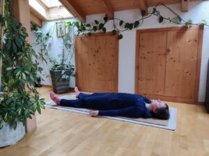 Frau auf Yogamatte in entspannter Position auf dem Rücken